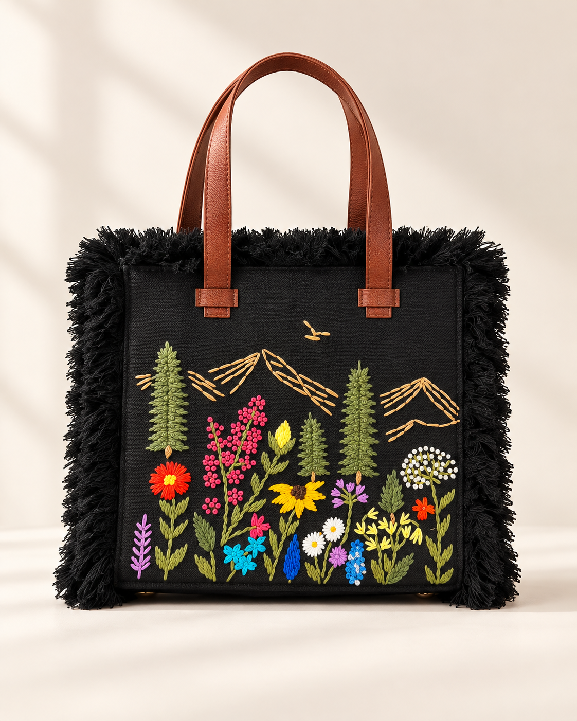 Black Meadow Fringe handbag with hand-embroidered wildflowers and mountains, front view